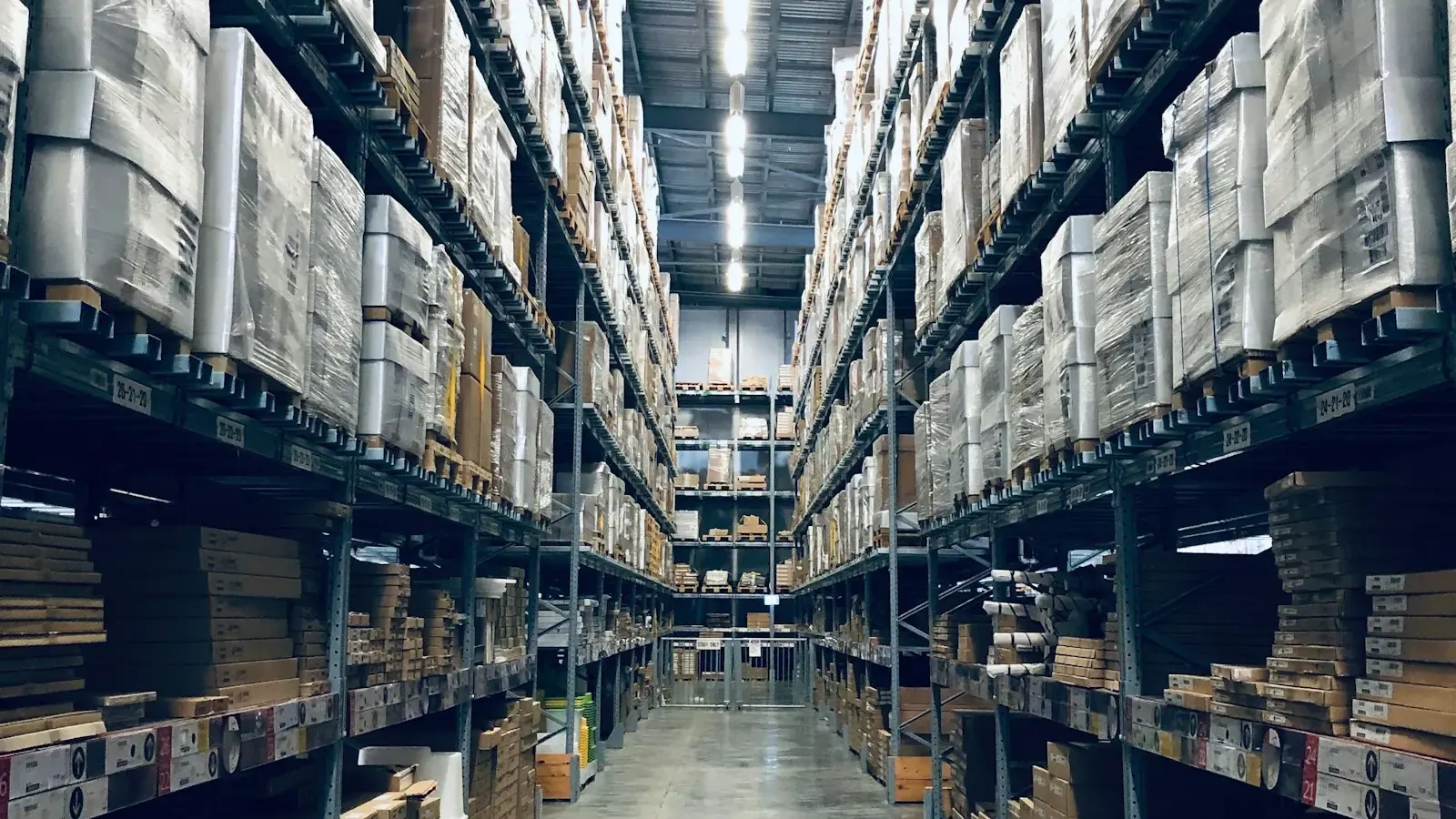 Warehouse aisle with racked inventory and a workstation on wheels